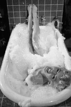 a woman laying in a bathtub filled with foam