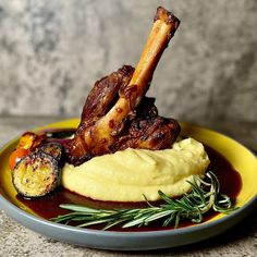 a yellow plate topped with meat and mashed potatoes next to a garnish