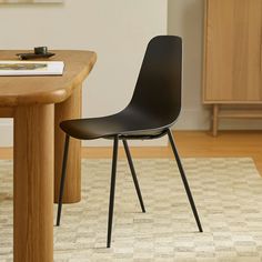 a black chair sitting next to a wooden table on top of a carpeted floor