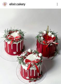 three red cakes with white frosting and decorations on top, one has a candle in the middle