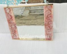 a mirror that is sitting on top of a white cloth covered tablecloth with the reflection of a bench in it