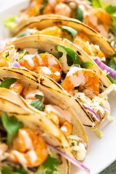 shrimp tacos are lined up on a plate