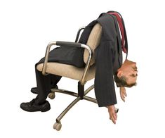 a man in a suit is upside down on a chair with his head under the seat