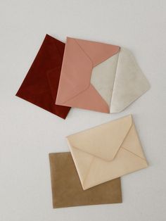 four envelopes are lined up on top of each other in different colors and shapes