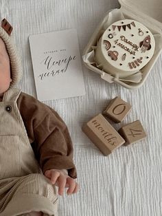 a baby laying on top of a bed next to wooden blocks