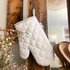 a white oven mitt hanging from the side of a wooden rack next to a potted plant