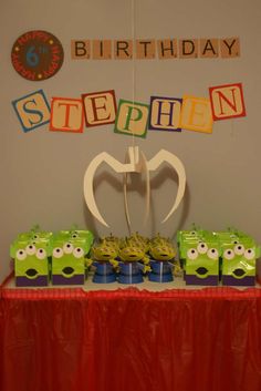 a table topped with lots of green and yellow boxes next to a red table cloth