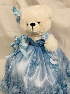 a white teddy bear wearing a blue dress