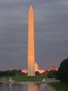 the washington monument in washington dc at dusk with reflecting water and trees on either side