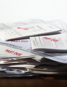 a pile of mail sitting on top of a table next to a cup filled with liquid