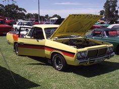 an old yellow car with its hood open on display at a car show in australia