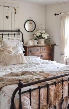 a bed with white linens and pillows in a bedroom next to a wooden dresser