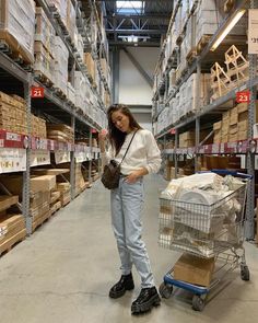 a woman standing next to a shopping cart in a warehouse