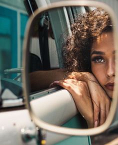 a woman's reflection in the side mirror of a car