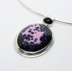 This sterling silver necklace is exquisitely enamelled in pink and black with a black onyx detail in the bail. The focal enamelled element features a beautiful constellation of black and pink colors which I've bezel set in sterling and fine silver with a bee cutout in the back. The bail is a sterling silver tube with a bezel set black onyx which is riveted to the back of the focal piece. The chain is a 16" italian silver omega necklace.This is a fun and unique abstract piece.Browse the Gracebour Unique Black Oval Pendant Necklace, Silver Necklace With Black Enamel In Distinctive Style, Unique Black Enamel Pendant Necklace, Handmade Black Enamel Necklace, Sterling Silver Pendant Necklace With Black Enamel, Unique Black Cabochon Necklace, Bee Cutout, Omega Necklace, Enamel Necklaces