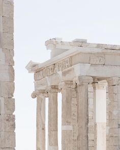 an old building with columns and a clock on the side of it's face