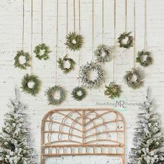 a white brick wall with wreaths hanging on it and a bed in the foreground