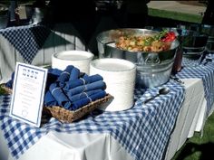 a blue and white checkered table cloth with napkins on it is set up outside