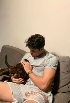 a man sitting on a couch petting a dog