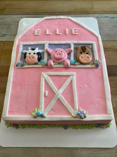 a pink cake decorated with farm animals and the word blue on it's side