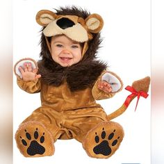 a toddler in a lion costume sitting on the ground with his hands up and smiling