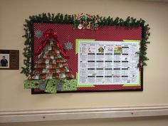 a bulletin board decorated with christmas trees and presents on the wall above it is an elf's calendar