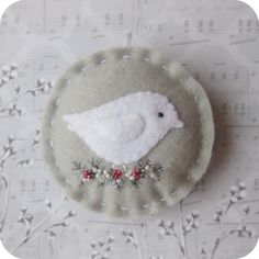 a small white bird sitting on top of a piece of fabric with red flowers around it