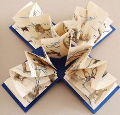 several folded pieces of paper on top of a blue and white board with ink splatters