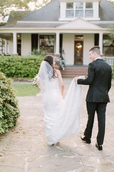 a bride and groom walking towards their house