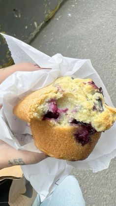 a person holding a muffin with blueberries in it