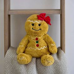 a yellow teddy bear with a red bow sitting on top of a bed next to a ladder