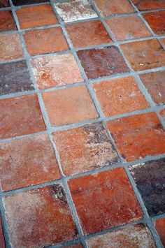 an orange and brown tile floor with some dirt on it