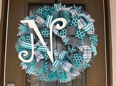 a blue and white wreath with the letter j on it is hanging on a door