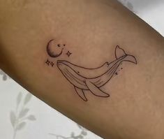 a tattoo on the arm of a woman with a whale and moon in its tail