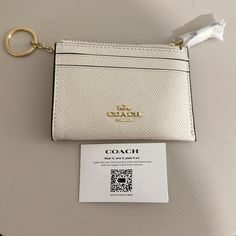 a white coach wallet and keychain sitting on top of a table next to a card