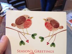 a person holding up a card with two birds on it and the words season's greetings