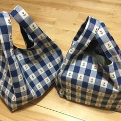 two bags sitting on top of a wooden floor covered in blue and white checkered fabric