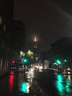 a city street at night with traffic lights and skyscrapers in the backgroud