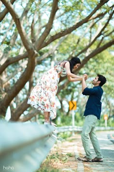 a man is holding the hand of a woman in front of trees and street signs