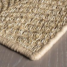 a close up view of a rug on the floor with wood and fabric in the background