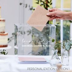 a person placing a piece of paper on top of a cake in a clear box