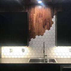 a kitchen with black cabinets and white hexagonal tile backsplash, stainless steel sink and dishwasher