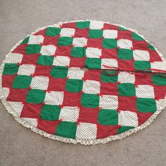 a red and green checkered tablecloth on the floor with white doily around it