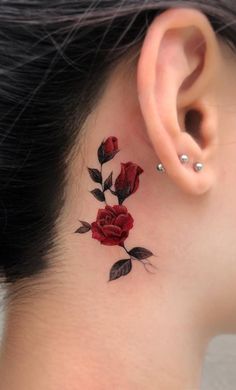 a woman's behind the ear tattoo with red roses