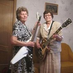 two women standing next to each other holding guitars