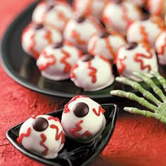 halloween treats are arranged in the shape of hands and balls on a black plate with pink border