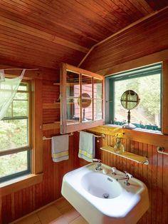 a bathroom with wood paneling and a white sink in the corner next to a window