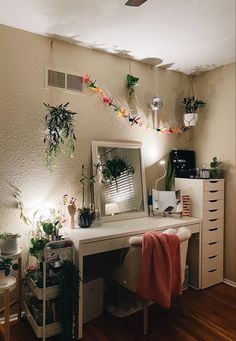 a desk with a mirror and some plants on it in front of a ceiling fan