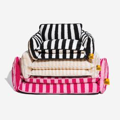 three pillows stacked on top of each other in pink and white striped fabric, one with black and white stripes