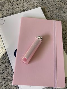 a pink notebook with a lighter on top of it